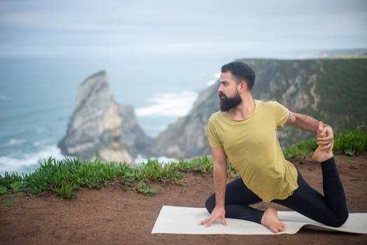 A man performs a yoga pose on a cliff overlooking the sea in Portugal, showcasing fitness and serenity.