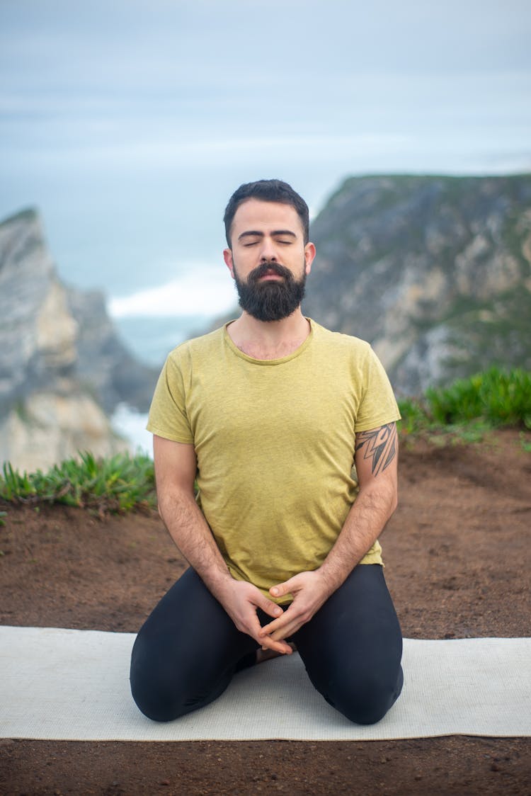 Man Meditating While Kneeling On Yoga Mat