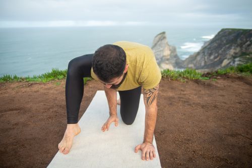 Free A man practices yoga on a cliff, showcasing strength and tranquility with the ocean in the background. Stock Photo