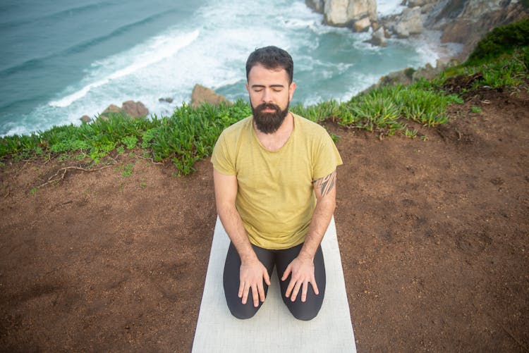 Man Meditating While Kneeling On A Yoga Mat 