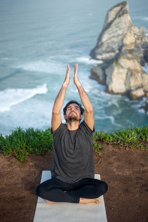 Free A man meditating on a yoga mat by the ocean in Portugal, embracing mindfulness. Stock Photo
