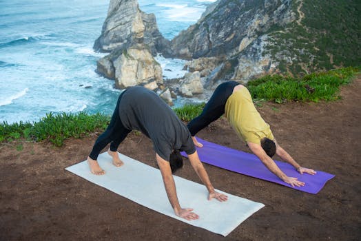 Two men practicing yoga on a cliffside overlooking the Atlantic Ocean in Portugal.