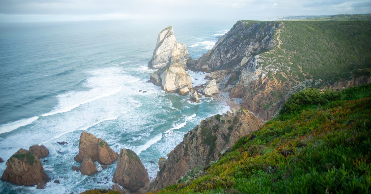 Scenic view of Portugal's rugged cliffs and waves crashing against the seashore.