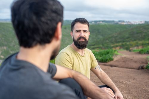 Free Two men sitting on a hillside in Portugal, enjoying a relaxed conversation. Stock Photo