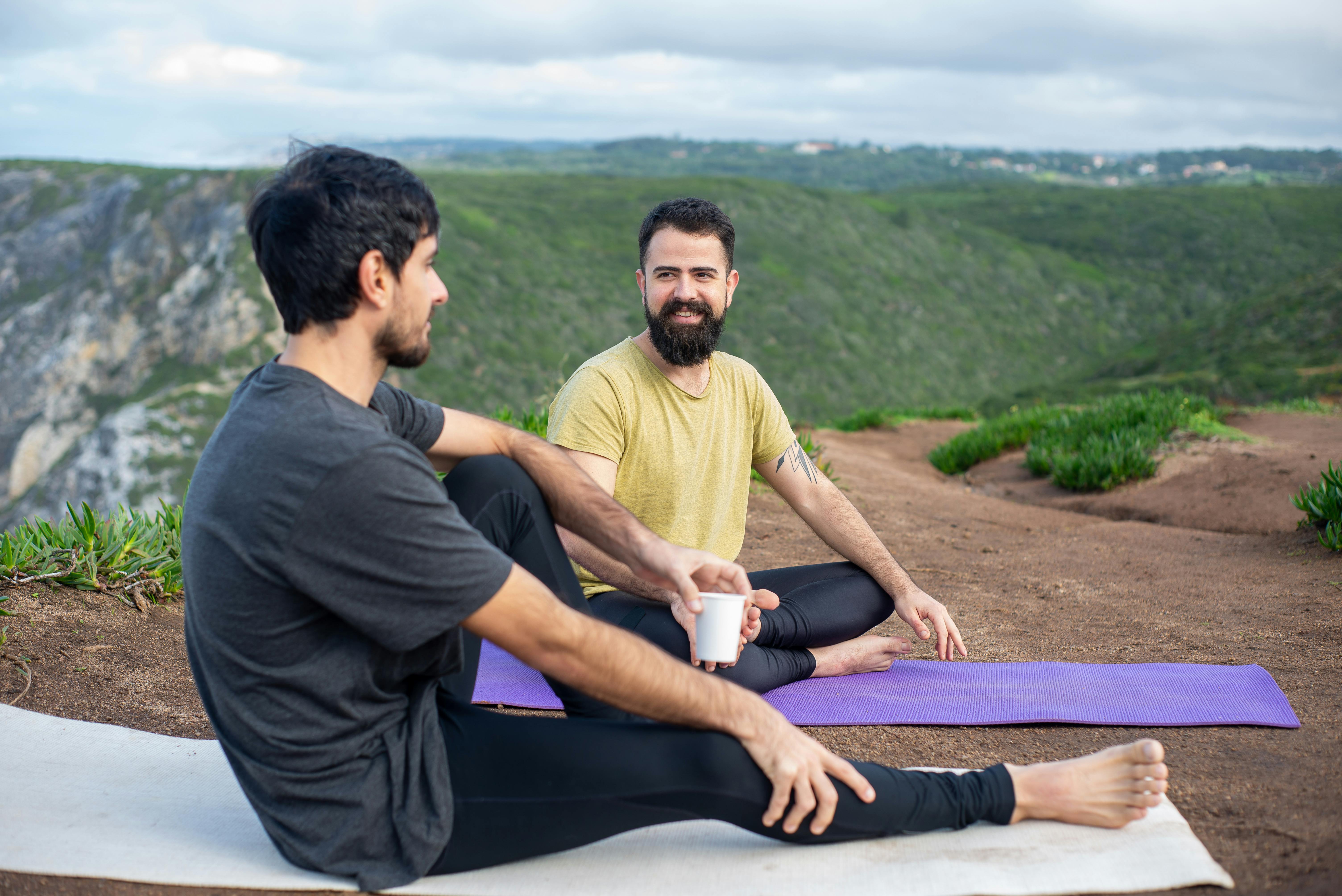 Men Sitting on Yoga Mats Near Green Hill