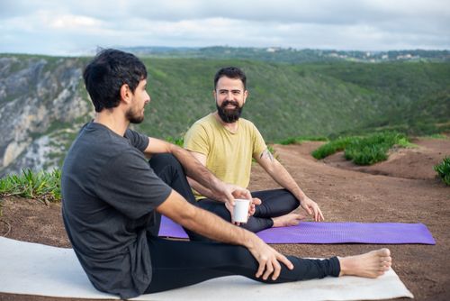 Free Two men sitting on yoga mats in a beautiful outdoor setting in Portugal, enjoying a relaxed moment. Stock Photo