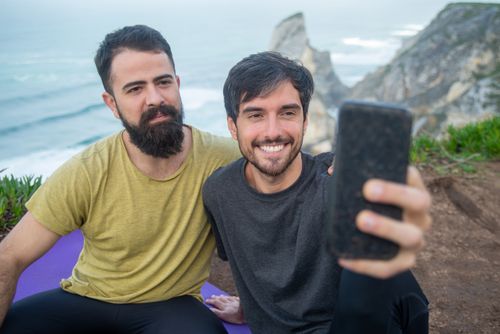 Free Two friends smiling and taking a selfie on scenic coastal cliffs in Portugal. Stock Photo