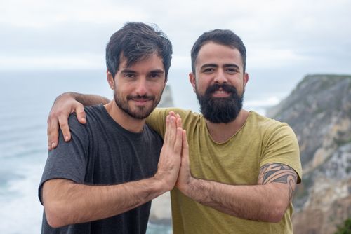 Free Two friends smiling and embracing near a coastal cliff, showcasing friendship and happiness outdoors. Stock Photo