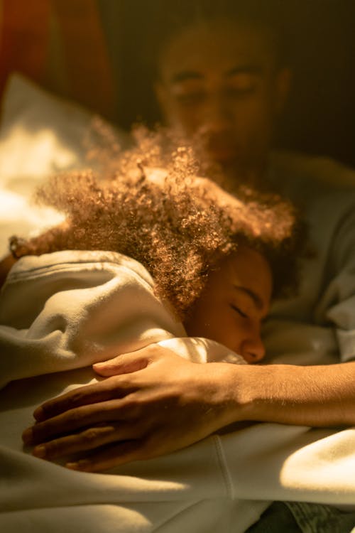 Free Siblings Lying on Bed while Hugging Each Other Stock Photo