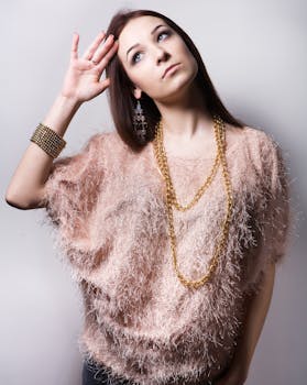 Young woman in stylish outfit posing with a thoughtful expression in studio.