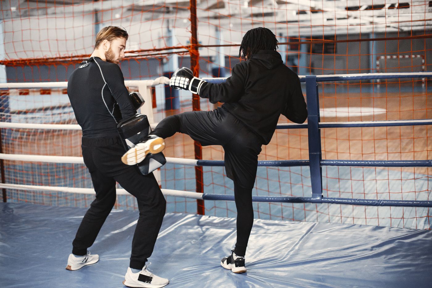 Two adult kickboxers sparring during a coached training session.