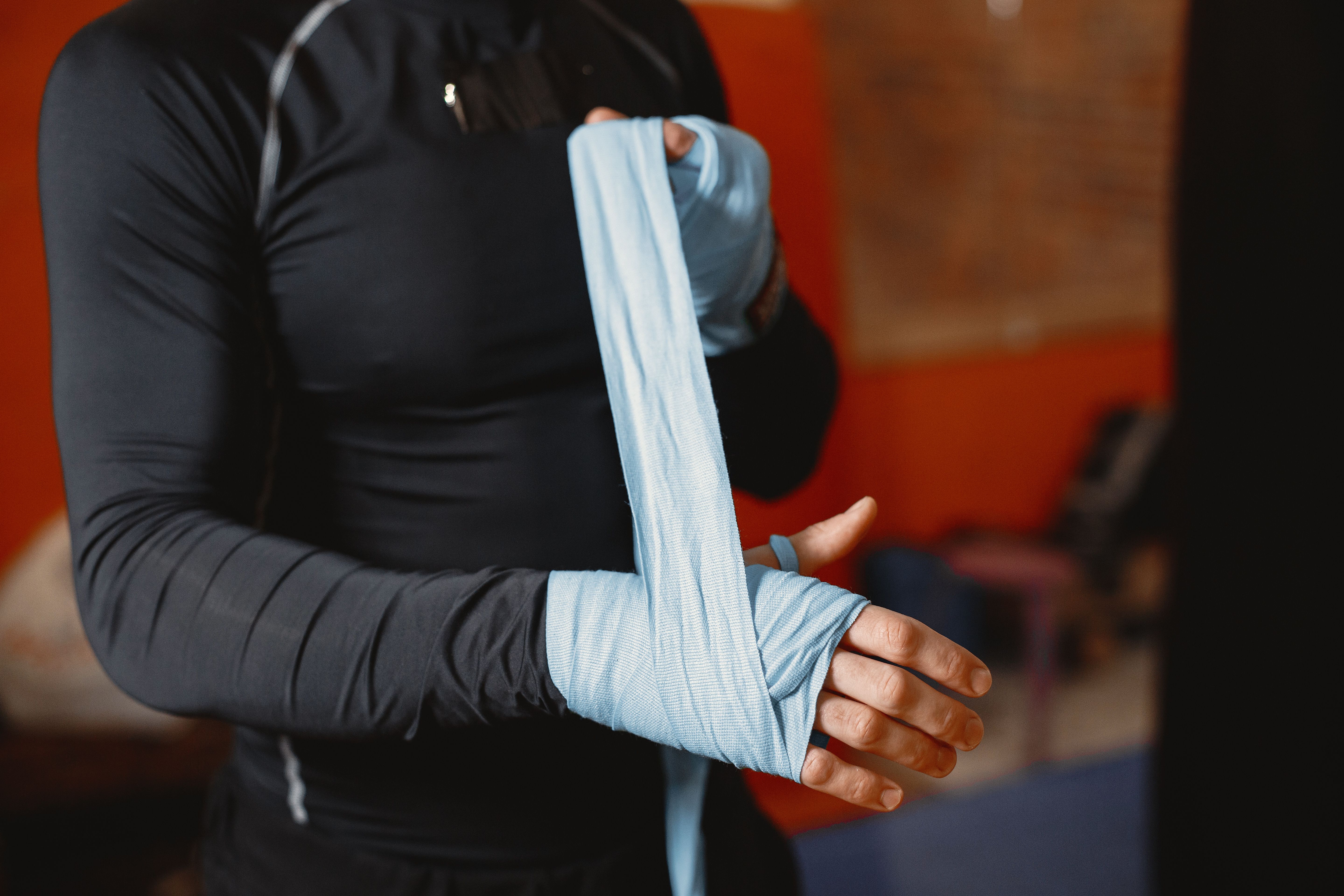 Close-up of a boxer wrapping his hands before training, warm low light on the hand wraps