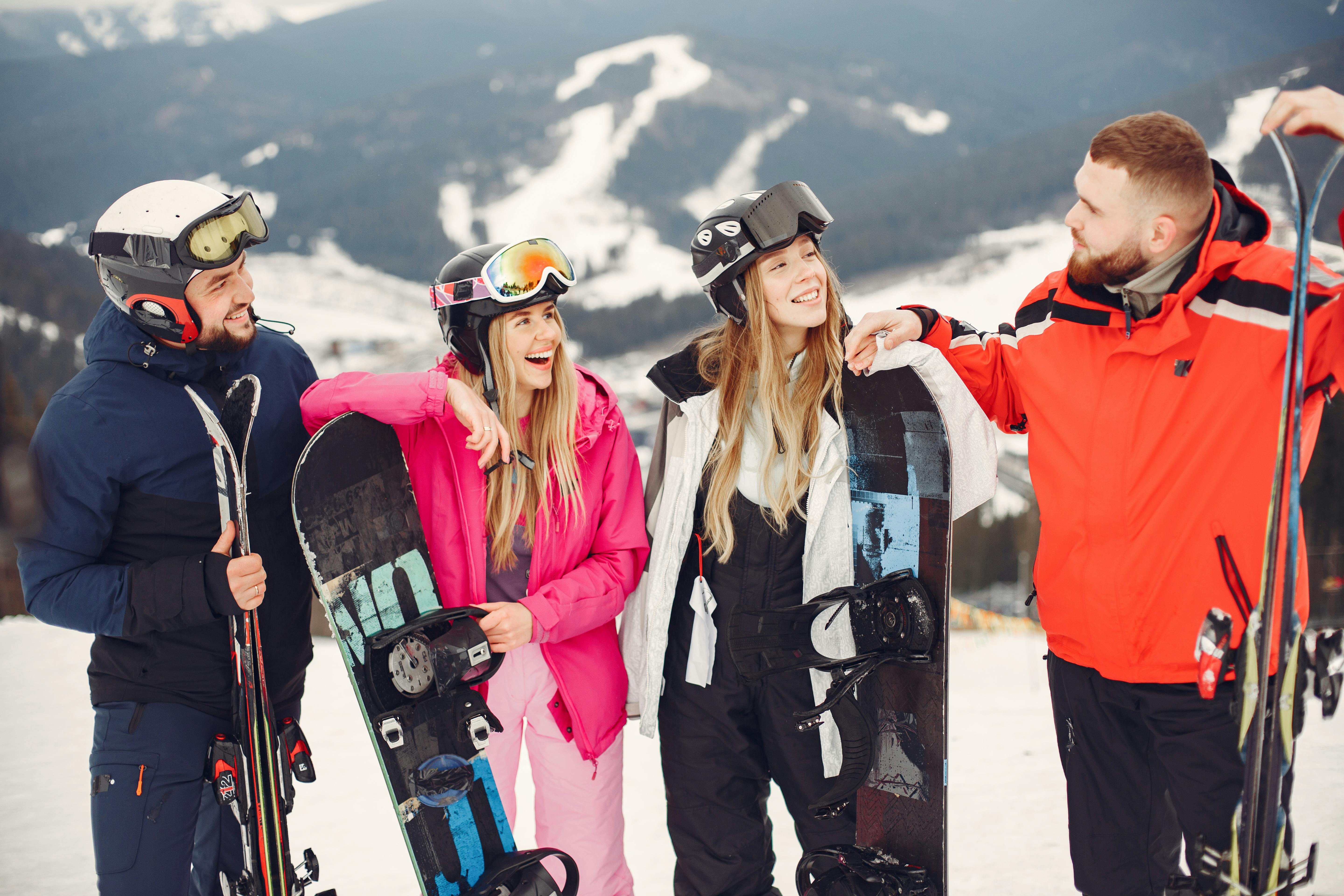 Prescription Goggle Inserts - Four friends laughing and posing with snowboards and skis on a sunny winter day in snowy mountains.