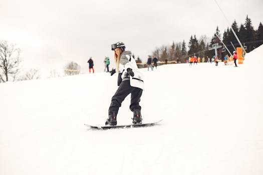 A woman snowboards down a snowy mountain slope, surrounded by winter scenery.