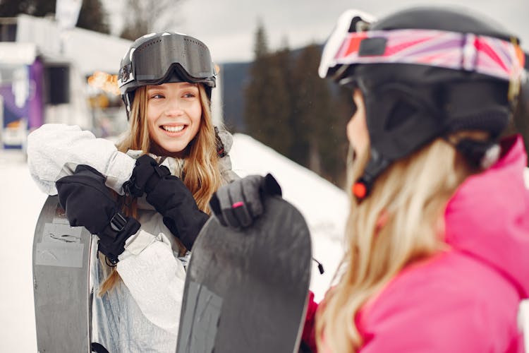 Smiling Girls With Snowboards In Mountains