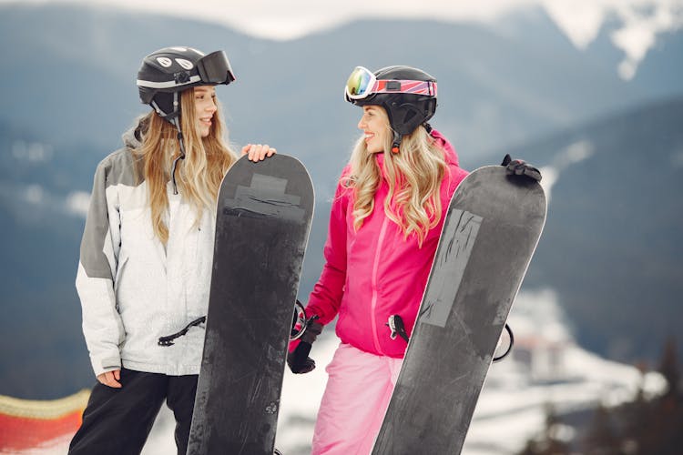 Smiling Women With Snowboards In Mountains