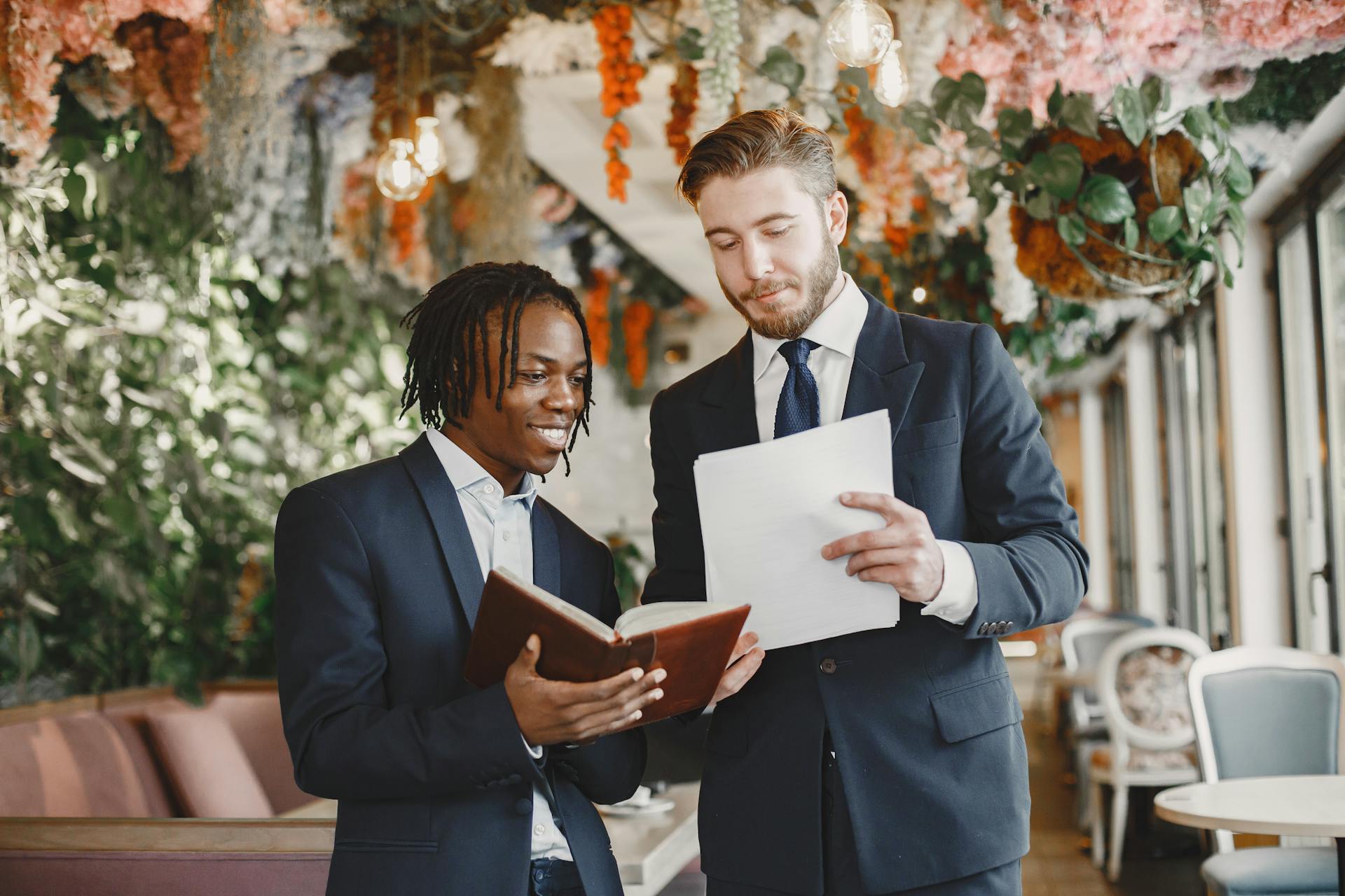 Two men in elegant suits discussing wedding plans at a beautifully decorated reception venue.