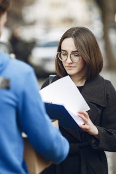 A woman receiving a package from a courier on a city street.