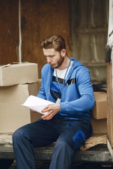 Young delivery worker reviews documents while surrounded by packages in a van.