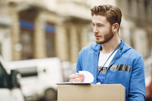 A Man in Blue Hoodie Holding a Cardboard Box