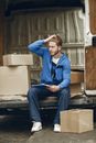 Man sitting beside Carton Boxes