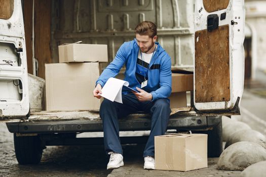 Caucasian man organizing delivery packages in a van, focused and working.