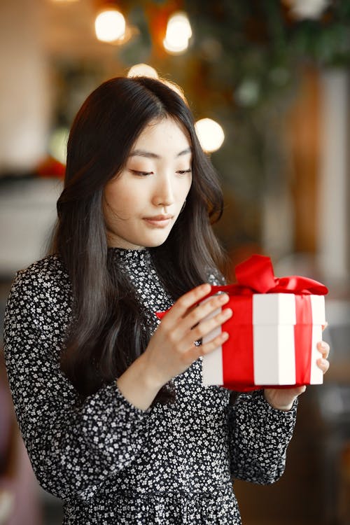 Woman with Black Long Black Hair Holding a Gift with Red Ribbon
