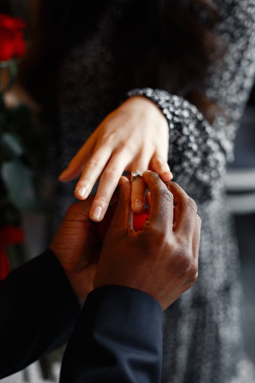 Free Close-up of a man placing an engagement ring on a woman's finger, capturing a personal moment. Stock Photo