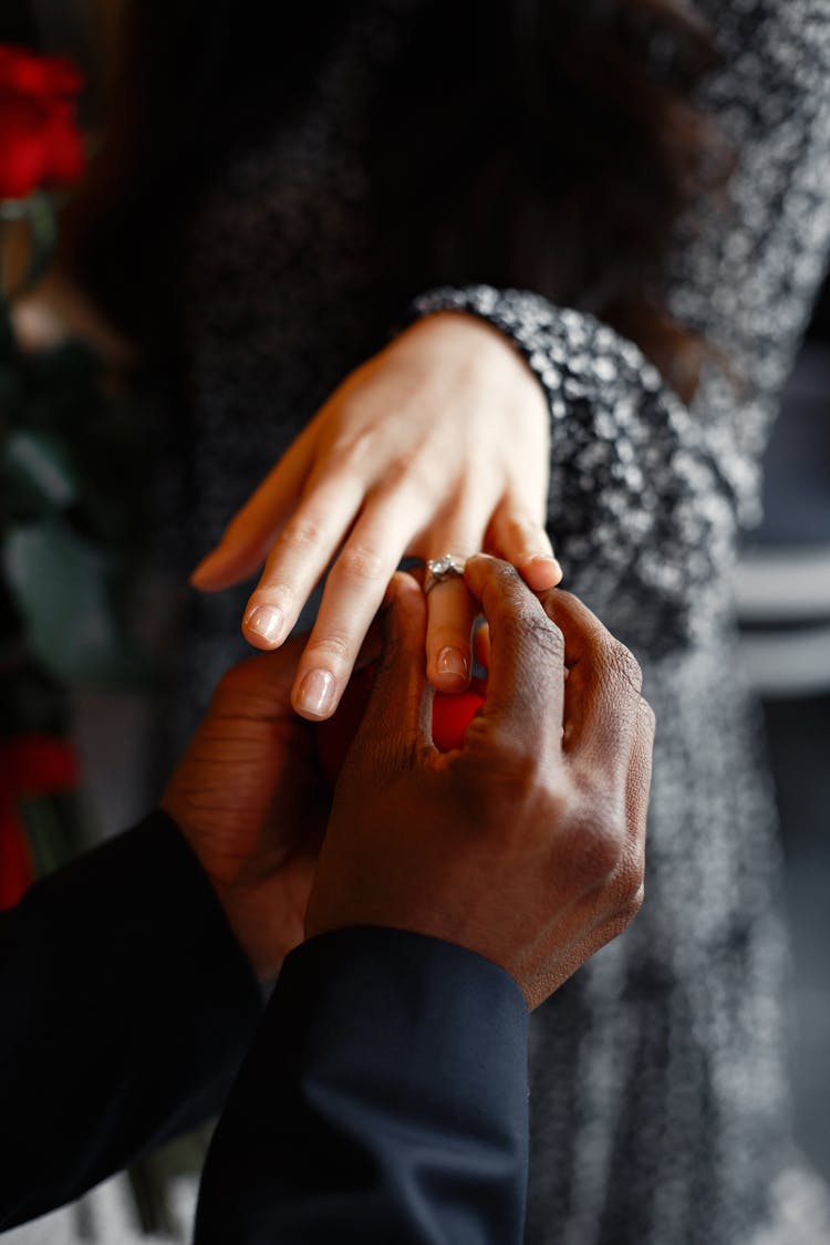 A Man Putting On A Ring Into A Woman's Finger