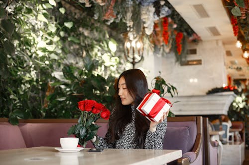 A Woman Holding a Gift Box and a Bunch of Red Roses