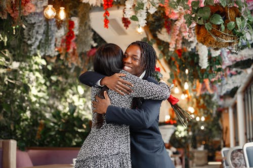 Elegantly Dressed Man and Woman Hugging in a Restaurant 