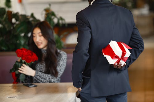 A Man in Black Suit Holing a Gift Box Behind Back