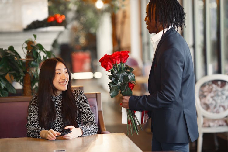 A Man Giving A Woman A Bunch Of Red Roses