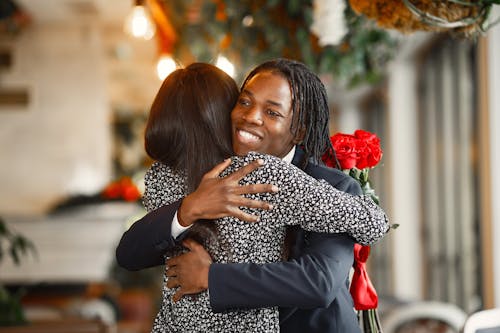 A Woman in Floral Dress Hugging a Man in Black Suit