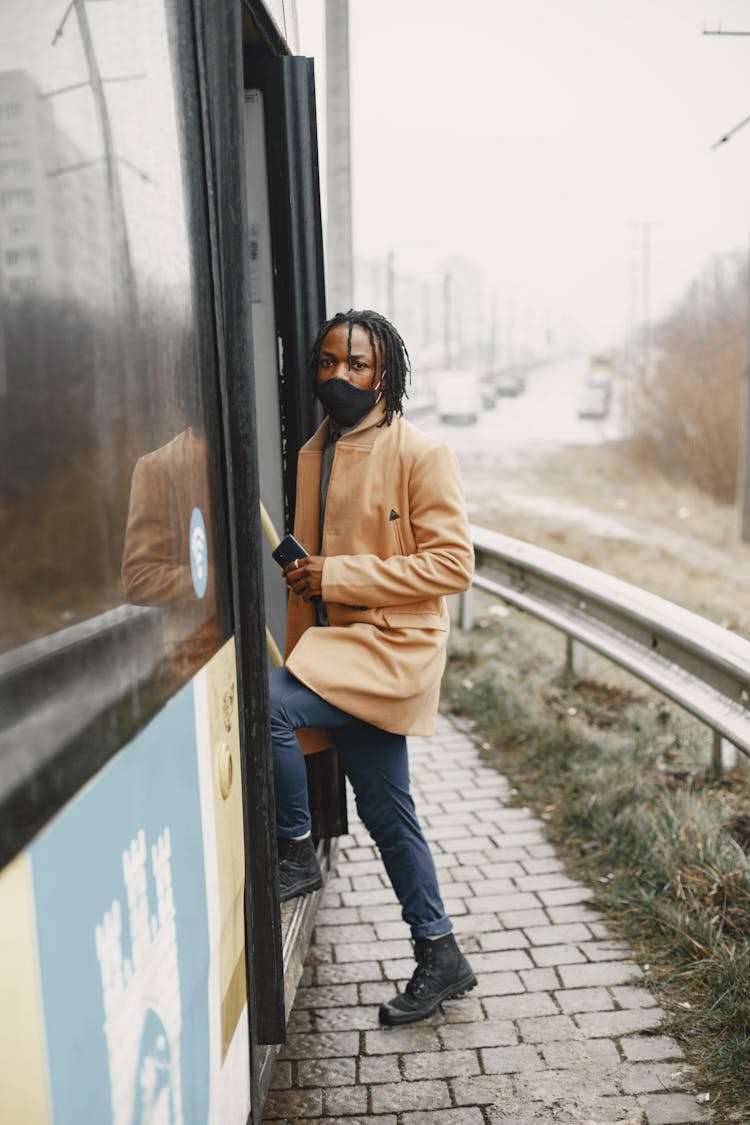 Young Man In A Face Mask Walking Into A Bus 