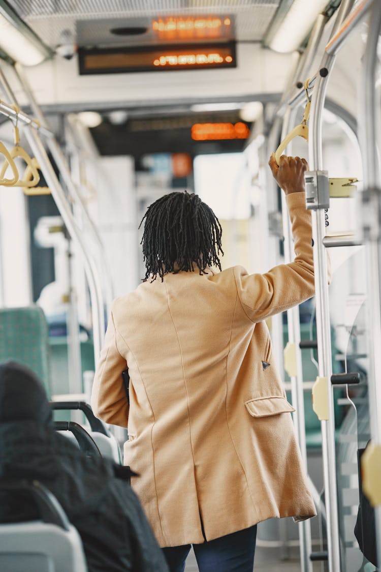 Back View Of Man In Brown Coat Holding Handle In Bus 