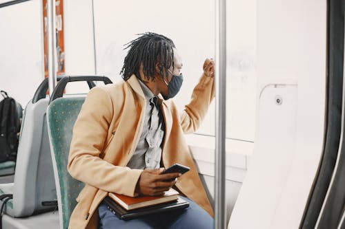 Man in Brown Coat Wearing Facemask Sitting Inside the Bus 