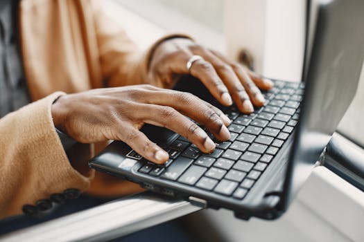 Close-up of hands typing on a laptop keyboard, showcasing detailed finger movements.