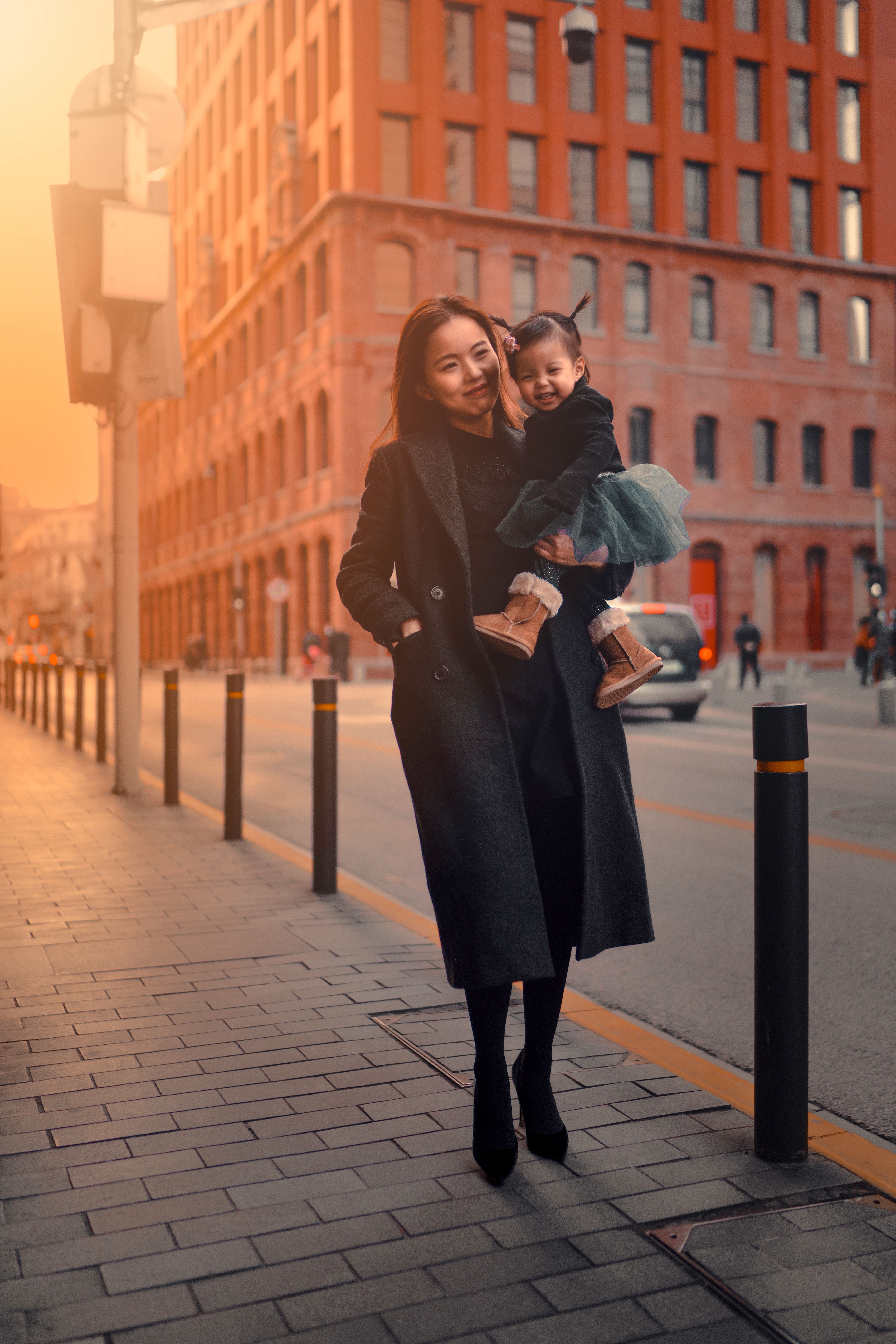 Woman in Black Coat Holding Her Baby on Sidewalk · Free Stock Photo