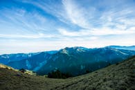 青翠山脉在广阔蓝天下令人惊叹，展现了大自然的宁静