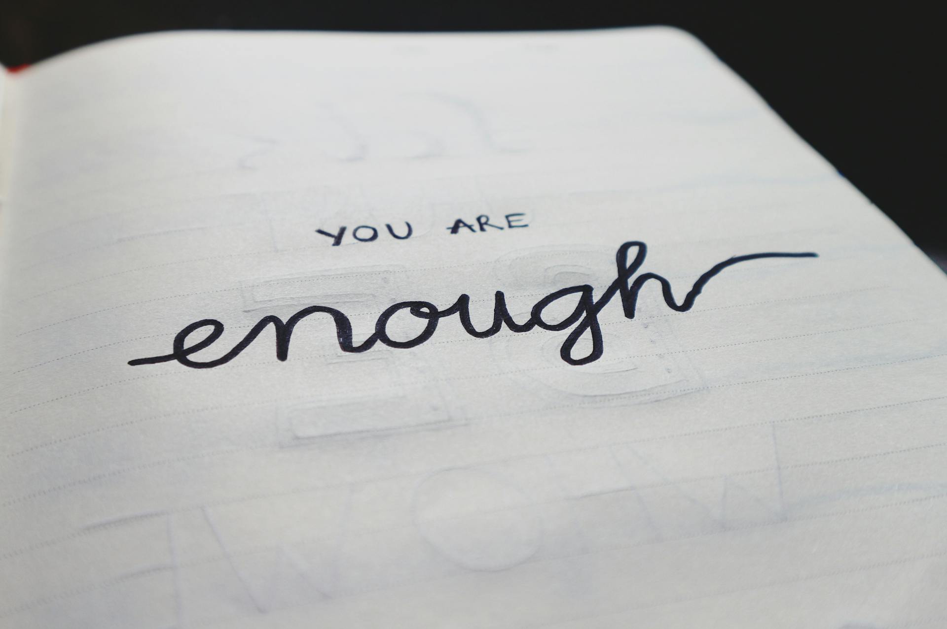 A close-up of a notebook page with motivational handwritten text: "You are enough."