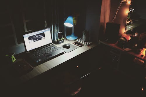 бесплатная Черный ноутбук рядом с черной компьютерной мышью внутри комнаты Стоковое фото