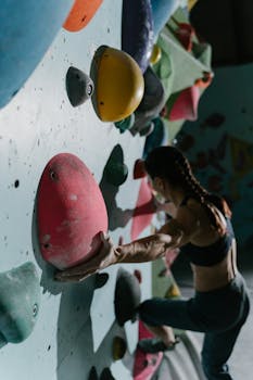 A woman engaged in bouldering on a challenging indoor climbing wall, showcasing strength and agility.