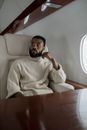 Man in White and Gray Striped Long Sleeve Shirt Sitting on White Leather Armchair