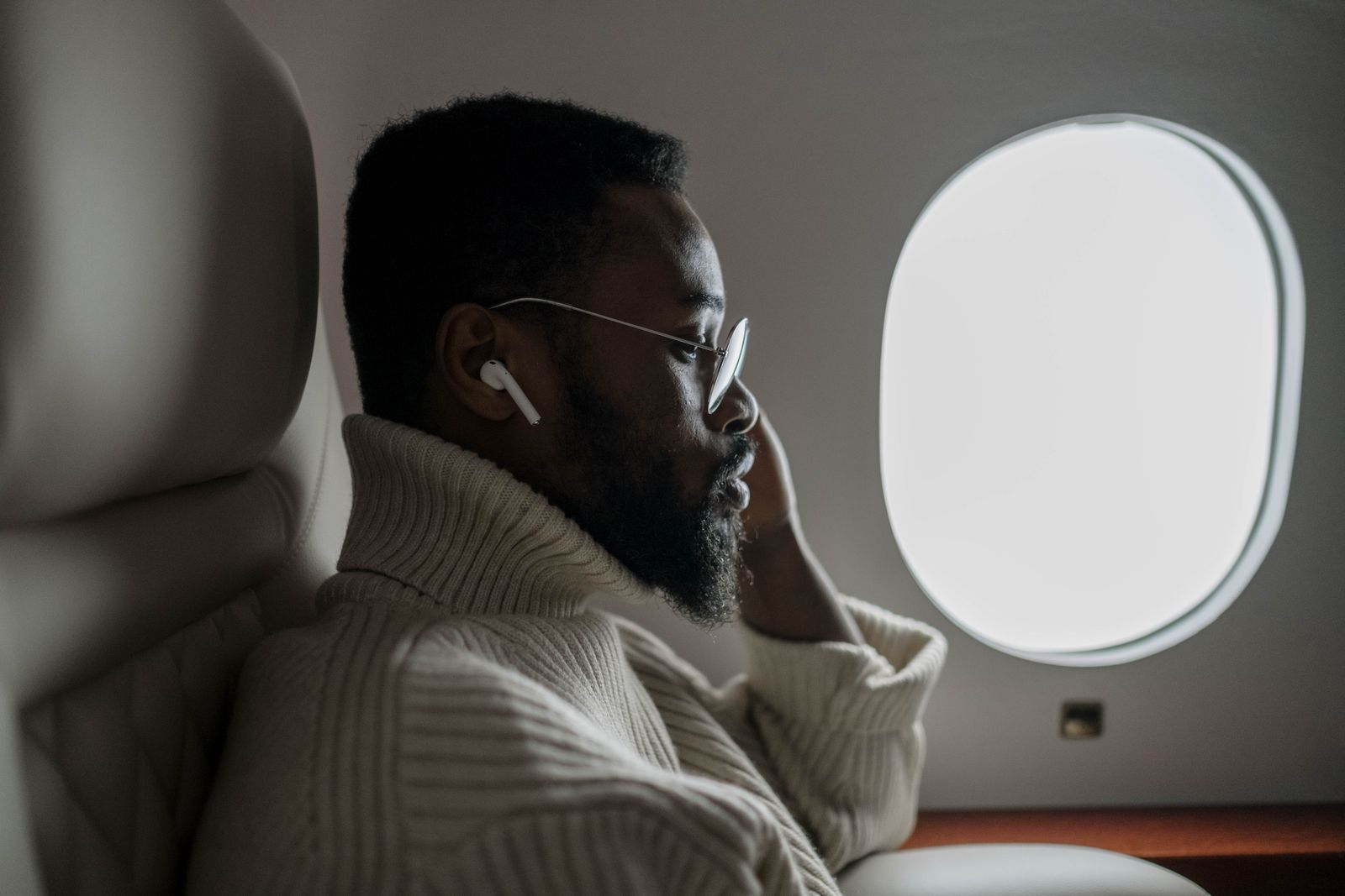 Airplane passenger seated by a window, matching the plane-sleeping neck support scenario.