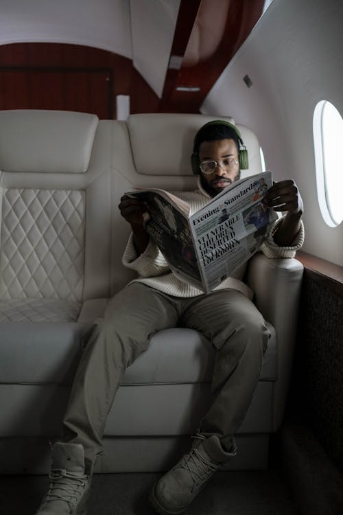 Free Photo of a Man with Headphones Reading a Newspaper Stock Photo