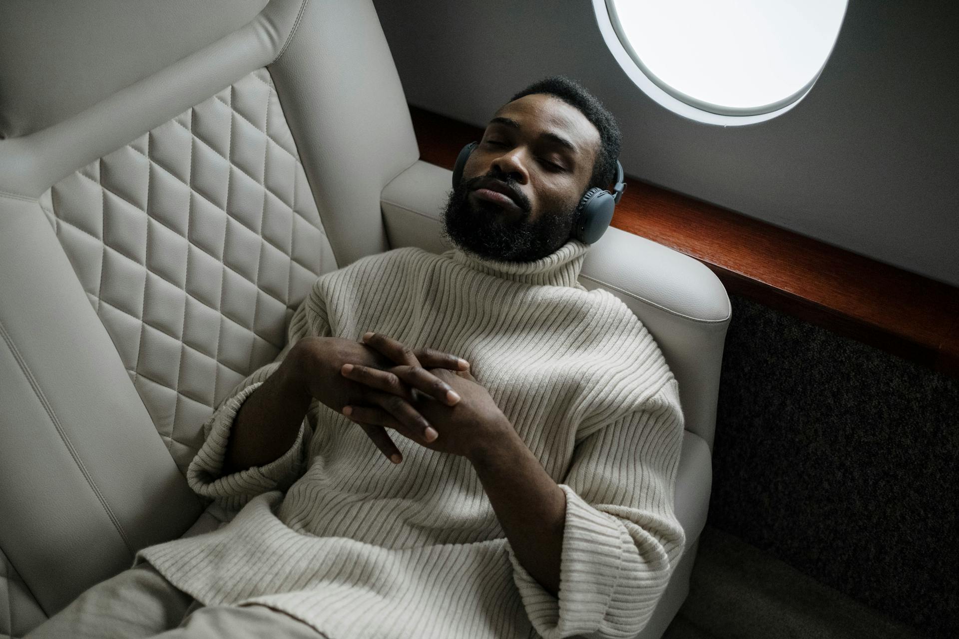 A businessman enjoys music on headphones while relaxing in a private jet. Luxurious travel concept.