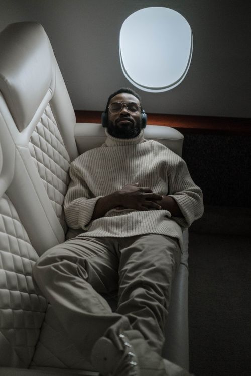 Free Man relaxing in airplane seat, listening to music with headphones. Stock Photo