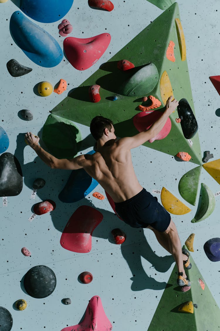 Topless Man In Shorts Climbing On Bouldering Wall