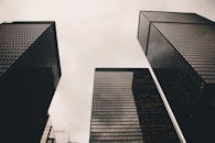 低角度视角下的现代摩天大楼，玻璃外墙映衬着多云的天空